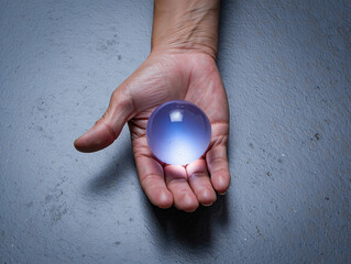 Hand holding a glowing crystal ball, symbolizing the future and fortune telling