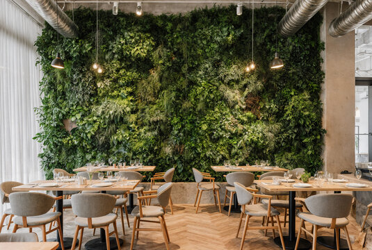 Sustainable cafe interior with living green wall and vertical garden in biophilic design - Powered by Adobe
