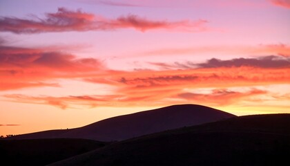 Fototapeta premium Fiery Sunset Hues Over Silhouetted Hilltops