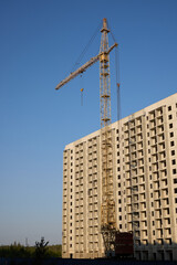 A tall crane watches over a large building project taking place in a bustling urban area