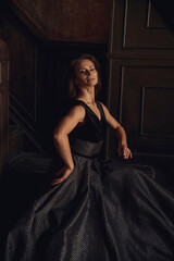 A dancer showcases her grace and strength while wearing an exquisite black gown. The setting features dark tones and intricate architectural details, enhancing the dramatic mood.