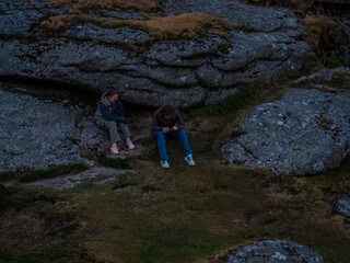 Family hiking on Dartmoor tors at sunset, silhouetted against dramatic skies in scenic moorland landscape