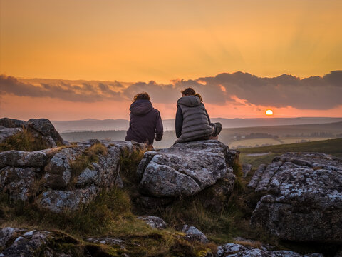 Family hiking on Dartmoor tors at sunset, silhouetted against dramatic skies in scenic moorland landscape - Powered by Adobe