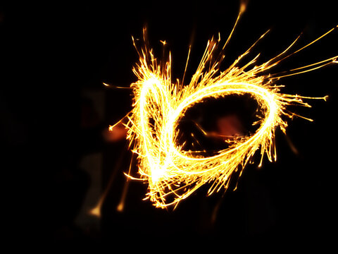 Heart shape drawn with a sparkler in the dark. Bright glowing fire effect captured in long exposure, symbolizing love, celebration, or romantic moments.