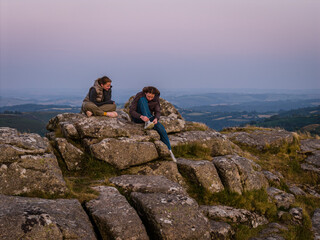 Family hiking on Dartmoor tors at sunset, silhouetted against dramatic skies in scenic moorland landscape © Alexey Fedorenko