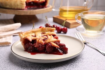 Piece of tasty cherry pie on grey textured table, closeup