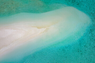 Tranquil aerial view of tropical sandbar with soft sandy shore, calming waves and clear sea lagoon. Beautiful abstract nature landscape and sunny shoreline scenery perfect summer vacation background