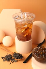 Tasty iced bubble tea and ingredients on orange background
