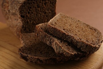 Pieces of fresh rye bread on brown background, closeup