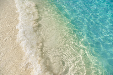 Tranquil beach closeup with soft sand and gentle ocean waves, calm blue sea under clear sky, peaceful tropical seascape perfect for summer vacation, relaxing coastal nature holiday background design