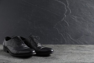 Pair of black leather shoes on grey surface, space for text