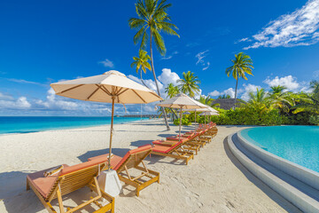 Gorgeous pristine beach scenic closeup. Umbrella leisure chairs beds poolside palm trees. Stunning exotic nature landscape. Luxury resort travel destination. Summer idyllic holiday tropical background