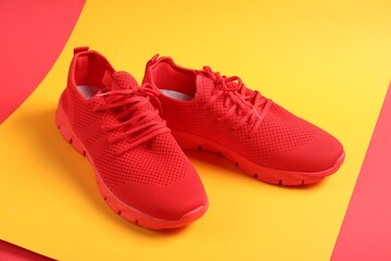 Pair of red sneakers on color background