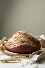 Loaf of fresh bread, flour and spikes on table, closeup