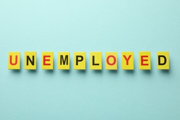 Word Unemployed on light blue background, top view