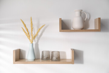 Wooden shelves with tableware and spikes in vase on white background