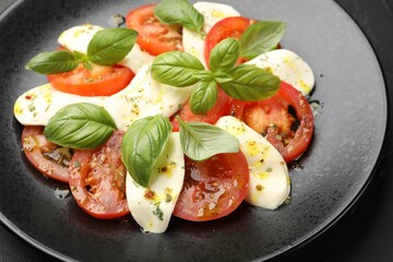 Tasty salad Caprese with mozzarella, tomatoes, basil and spices on table, closeup
