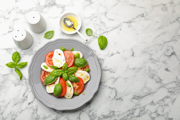 Tasty salad Caprese with mozzarella, tomatoes, basil and spices on white marble table, flat lay. Space for text