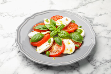 Tasty salad Caprese with mozzarella, tomatoes, basil and spices on white marble table, closeup