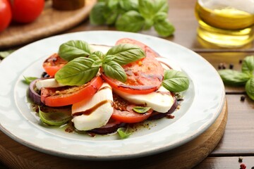 Tasty salad Caprese with mozzarella, tomatoes, basil and spices on wooden table, closeup