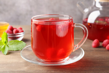Aromatic raspberry tea, berries and mint on wooden table, closeup
