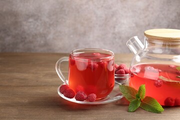 Aromatic raspberry tea, berries and mint on wooden table, closeup. Space for text