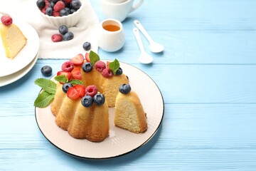 Tasty Bundt cake with berries, honey and mint on light blue wooden table, closeup. Space for text