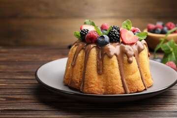 Tasty Bundt cake with berries, chocolate and mint on wooden table, closeup