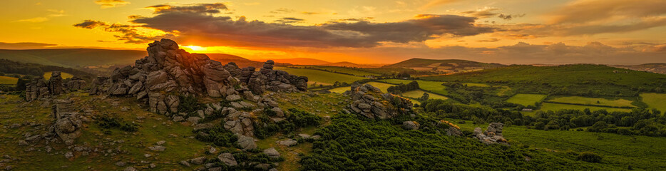 Family hiking on Dartmoor tors at sunset, silhouetted against dramatic skies in scenic moorland landscape