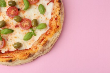 Delicious pizza with tomatoes, olives and basil on pink table, above view. Space for text