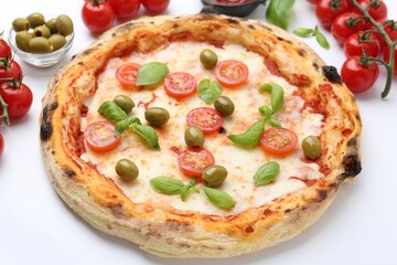 Delicious pizza with tomatoes, olives and basil on white table, closeup