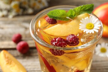 Iced tea. Refreshing drink with peach, raspberries and chamomile on table, closeup