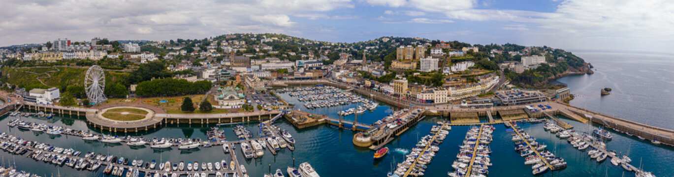 Aerial view of Torquay Marina on a sunny day, featuring yachts, boats, promenade, and blue sea along the English Riviera coastline