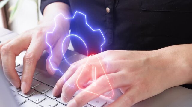 Hands of a female executive concentrating while working on her laptop while a glowing icon of a gear with a Warning sign floats by