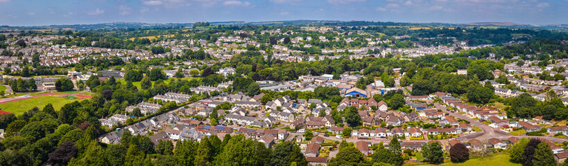 Fototapeta premium Aerial view of Tavistock, Cornwall, on a sunny day showing town layout, rooftops, and surrounding green countryside
