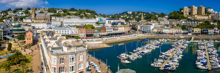 Aerial view of Torquay Marina on a sunny day, featuring yachts, boats, promenade, and blue sea...