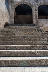 Historic stone courtyard with arched staircases, ancient sculptures in a Mediterranean old town