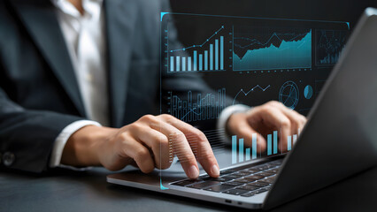 Man in suit typing on laptop with financial charts overlayed on the screen in a dark setting