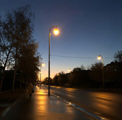Sidewalk next to a city street in the evening.