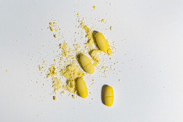 top view of light background and yellow tablets with scattered powder