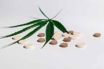 A view of one large pill which is on a light background with a sheet of medical cannabis and other pills on the background