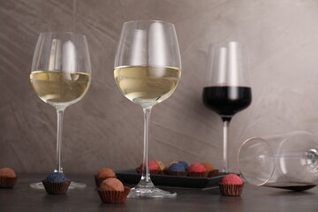 Tasty wine in glasses and truffle bonbons on grey table, low angle view