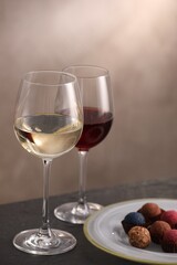 Delicious truffle bonbons and wine on black table against grey background