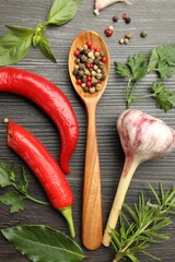 Different aromatic herbs, products and spoon with peppercorns on dark wooden table, flat lay