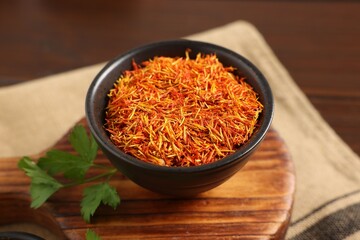 Saffron in bowl and coriander on table, closeup. Aromatic spices