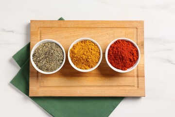 Different aromatic spices on white marble table, top view