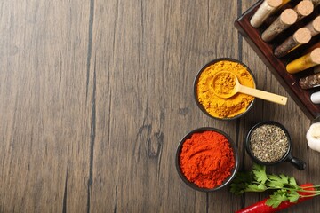 Different aromatic spices on wooden table, flat lay. Space for text