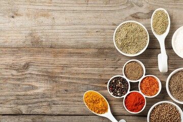 Different aromatic spices on wooden table, flat lay. Space for text