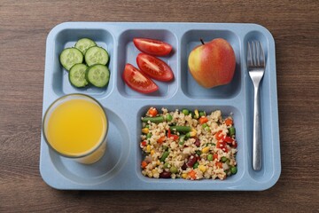 Plastic tray with tasty food, orange juice and fork on wooden table, top view. School lunch