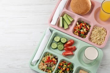 School lunch. Plastic trays with tasty food, milk and orange juice on light wooden table, top view. Space for text